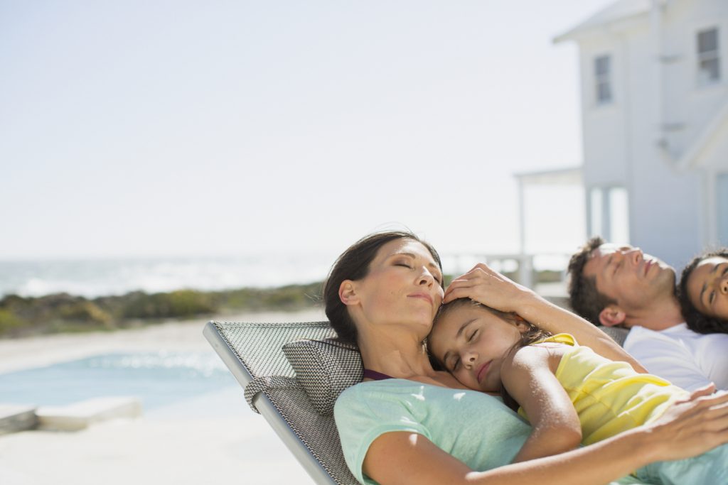 Family sleeping in lounge chairs at poolside