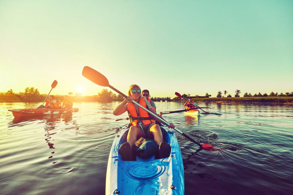 Family kayaking together in the fall on a calm waterway at sunset, wearing life jackets and enjoying the great outdoors on Hilton Head Island